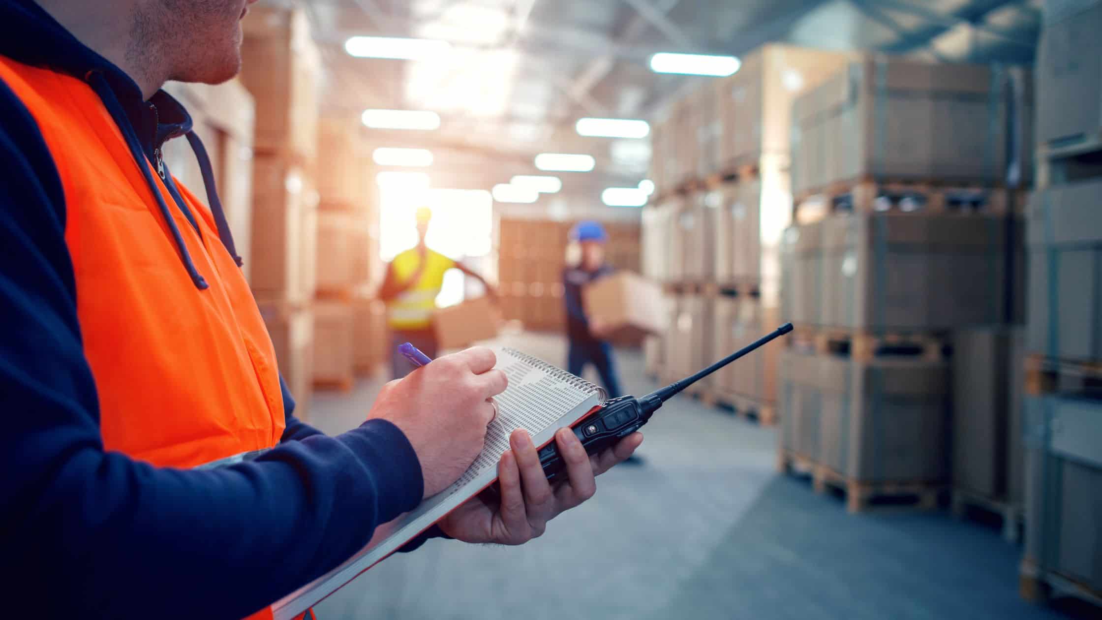 Worker with clipboard in warehouse for safety check